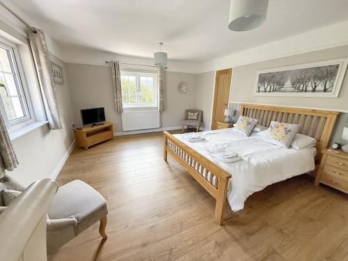 a bedroom with a large bed and a television at Barn Cottage in Minehead