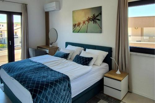 a bedroom with a blue and white bed and a window at Penthouse Apartment Maya with Pool and Jacuzzi in Sveti Anton