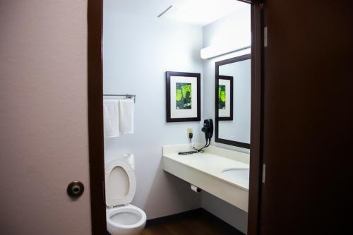 a bathroom with a toilet and a sink and a mirror at MainStay Suites Chicago Hillside in Hillside