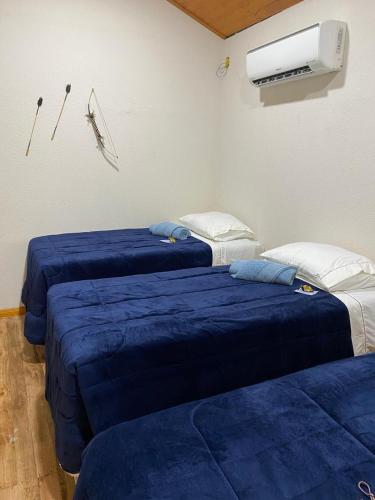 a room with two beds with blue sheets and a heater at Espaço Luna in Gramado