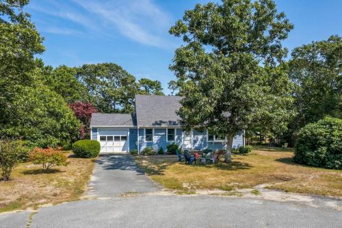 a blue house with a tree and a driveway at Sun Room Beaches and Dog Welcome in Chatham
