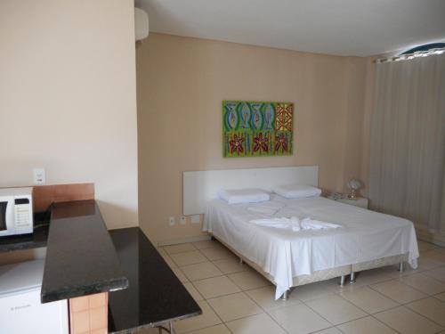 um quarto com uma cama branca numa cozinha em Cachoeira Apart Hotel em Cachoeira