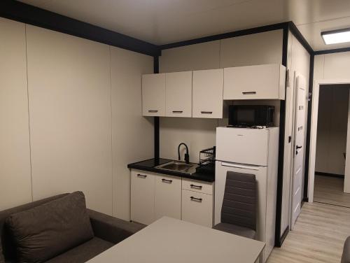 a small kitchen with white cabinets and a white refrigerator at Domki u Krukow in Łuka