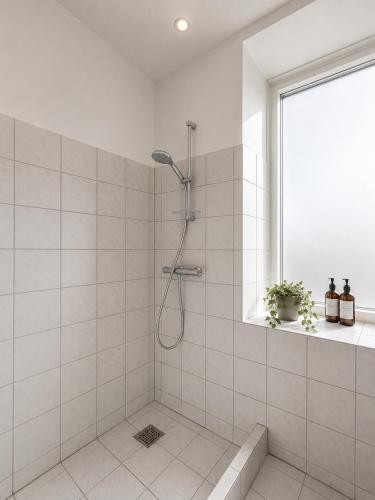 a white bathroom with a shower with a window at NØ -Central Apartment Odense C in Odense