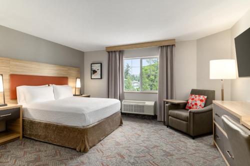 a hotel room with a bed and a chair at Candlewood Suites Oak Harbor by IHG in Oak Harbor