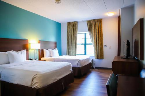 a hotel room with two beds and a television at MainStay Suites Chicago Hillside in Hillside