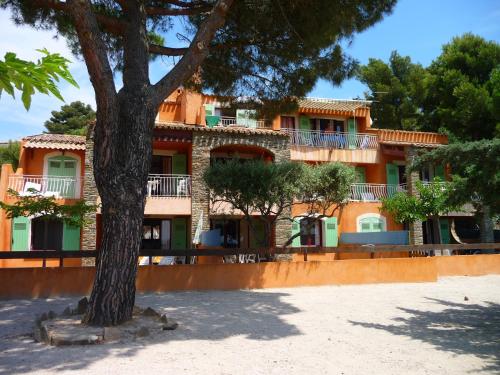 un bâtiment orange avec un arbre devant lui dans l'établissement Villa L'ensoleillade, à La Londe-les-Maures