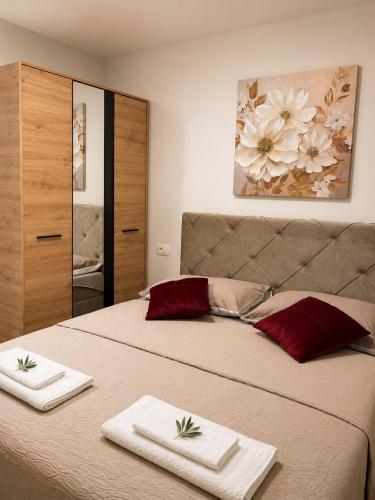 a bedroom with two beds with towels and a painting at Apartmani Đurišić in Posušje