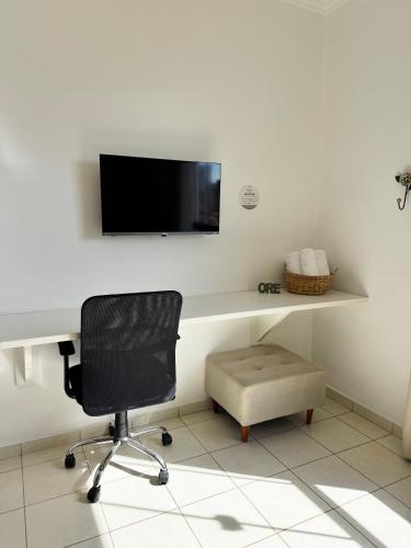 a desk with a chair and a television on a wall at Pousada da Mariinha in São Lourenço