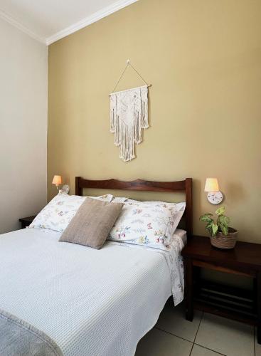 a bedroom with a bed with white sheets and pillows at Pousada da Mariinha in São Lourenço