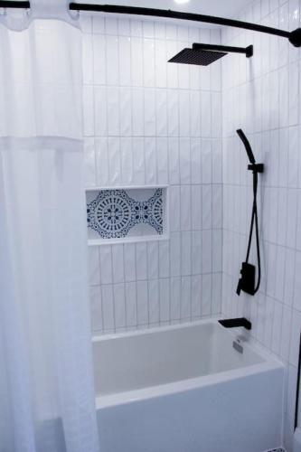 a white bathroom with a tub and a white tile wall at 4 Guest Suite with Waterfront Views at Fancie's PEC - Suite 2 in Belleville