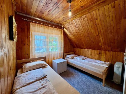 two beds in a room with wooden walls at Planinski vuk rooms in Žabljak
