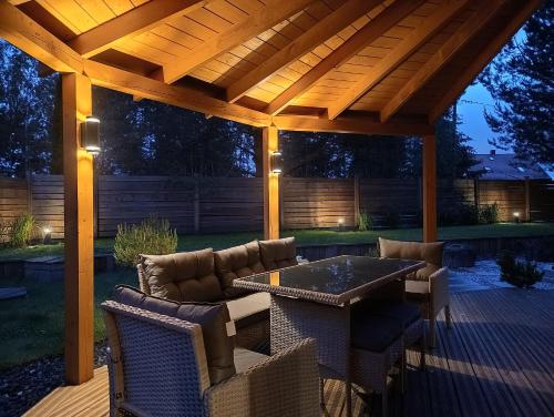 a patio with a wooden pergola with chairs and a table at Domy Kopułowe 5th Wymiar in Skrybicze