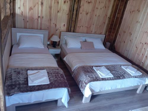two beds in a room with wooden walls at Četiri sestre in Žabljak