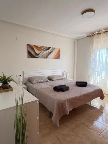 a bedroom with a bed with two black towels on it at SiCasa Punta Prima in Punta Prima