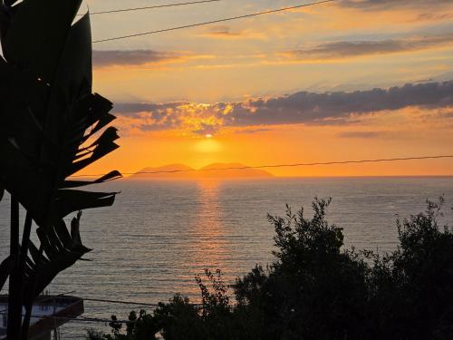 a sunset over the ocean with mountains in the distance at Villa Meminaj in Vlorë