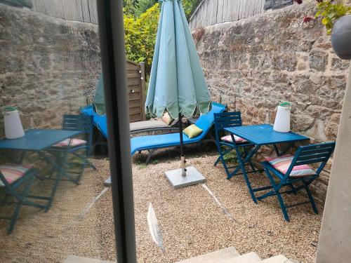 a patio with two tables and an umbrella at La Suite 27 bis, maison de charme avec terrasse, proche gare et centre in Guingamp
