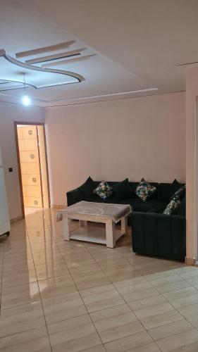 a living room with a green couch and a table at Appartement propre in Saïdia
