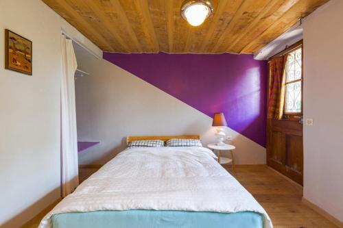 a bedroom with a large bed with a purple wall at Farm & Chill Guesthouse in Thierrens