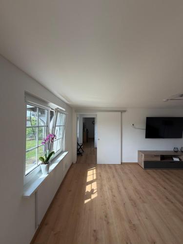 a living room with a flat screen tv and a wooden floor at Strandhaus Störtebeker in Koserow