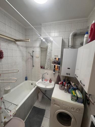 a bathroom with a tub and a sink and a washing machine at Egry Rooms in Veszprém
