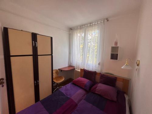 a bedroom with a bed with purple sheets and a window at Egry Rooms in Veszprém