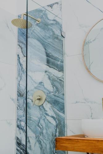 a shower in a bathroom with a marble wall at Sand In My Shoes in Muizenberg