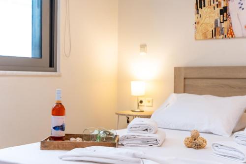 a bedroom with a bed with a bottle of wine and towels at Rosso 3 City Centre Apartment in Heraklio