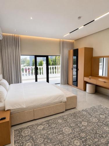 a bedroom with a large bed and a large window at Al Reef Garden in Sohar