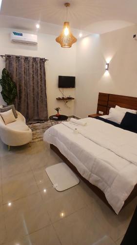 a bedroom with a large white bed and a chair at PaoLia Meublé 3 in Cotonou