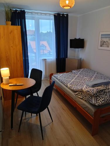 a bedroom with a bed and a table and chairs at Pokoje gościnne u Aleksandry in Hel
