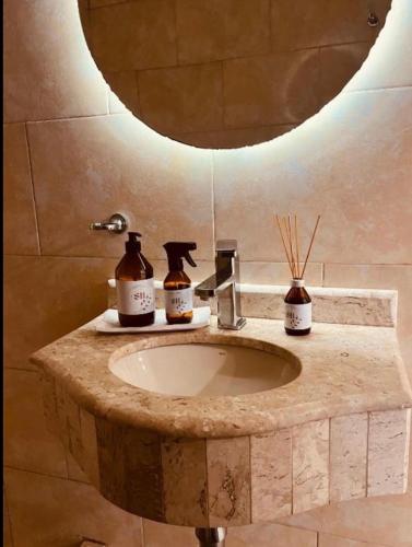 a bathroom sink with two bottles of soap and a mirror at SHINY House 2 habitaciones in Clorinda