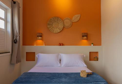 a bedroom with a bed with an orange wall at Vila Caetité - Mucugê in Mucugê