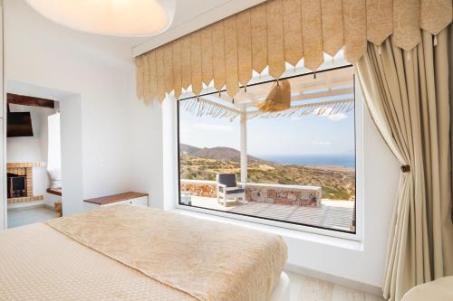 a bedroom with a large window with a view of the ocean at Mythos Villa Above the Sunset in Karpathos