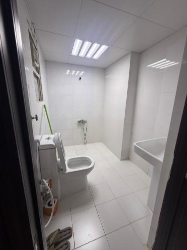 a white bathroom with a toilet and a sink at Royal International in Abu Dhabi