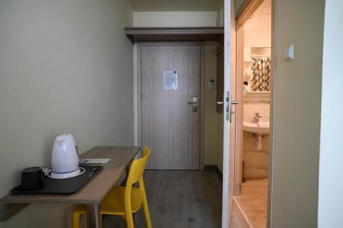 a room with a table and yellow chairs and a door at Dom Żeglarza in Puck