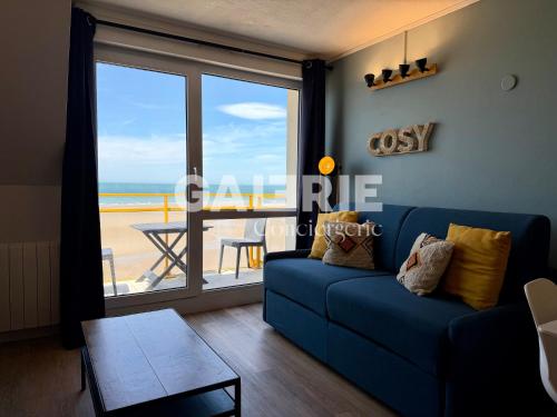 a living room with a blue couch and a view of the beach at GC - Le Panorama - Front de Mer in Wissant