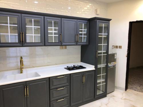a kitchen with gray cabinets and a sink and a refrigerator at شالية السلطان 1 in Khamis Mushayt