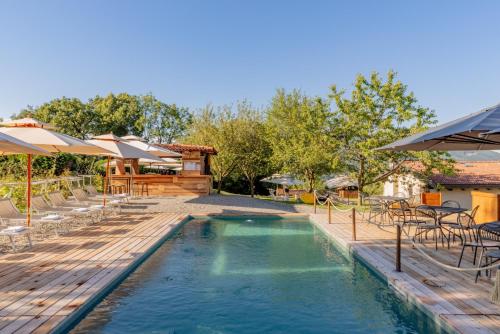a pool with tables and umbrellas and a house at Agriturismo La Nevera in Lanzo dʼIntelvi