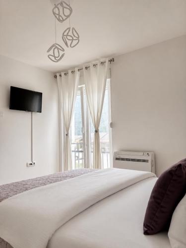 a white bedroom with a bed and a window at Lux Apartman Casablanca in Plužine