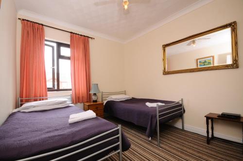 a hotel room with two beds and a mirror at The Rathmore in Cambridge
