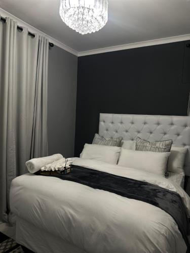 a bedroom with a large white bed with a chandelier at P Daisy in Rundu