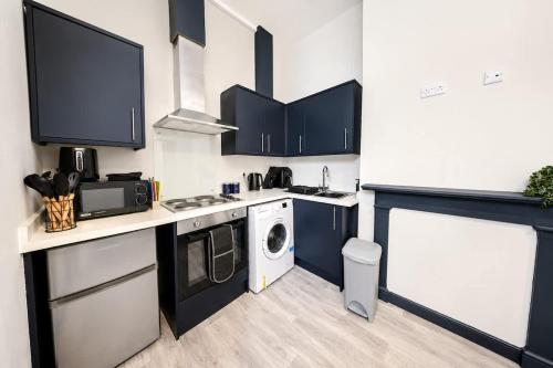 a kitchen with blue cabinets and a washer and dryer at Amazing City Centre Apartment in Derby