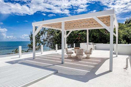 a pavilion with a table and chairs on the beach at White Sands Beach House in Maya Beach