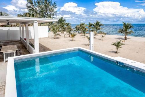 a blue swimming pool next to the beach at White Sands Beach House in Maya Beach