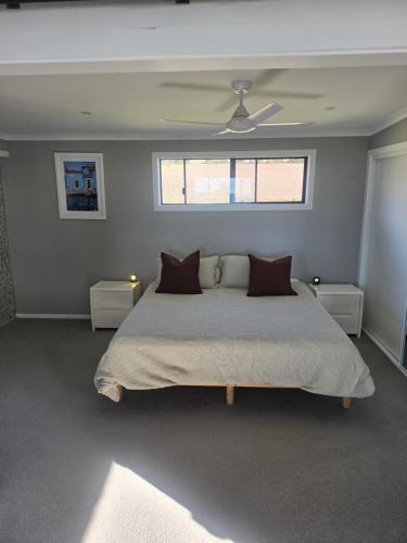 a bedroom with a large bed and two windows at Tiatukia Beach House in North Shields