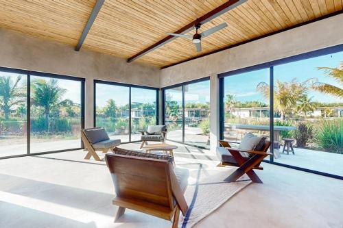 a living room with furniture and large windows at Seabird - Villa 17 in Placencia