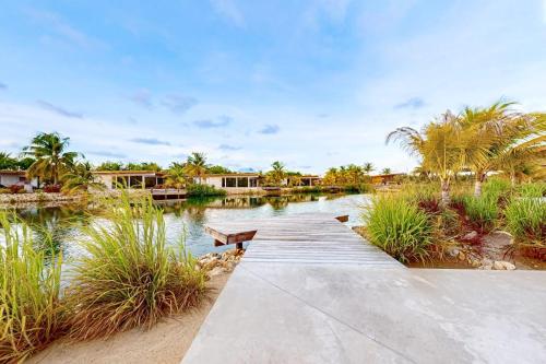 a wooden walkway over a lake with palm trees at Seabird - Villa 17 in Placencia