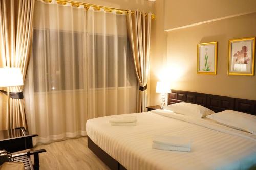 a bedroom with a large bed with white sheets at Taris Art Hotel Phrae in Phrae