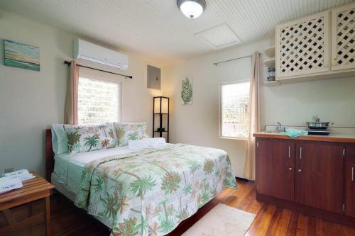 a bedroom with a bed and a table and two windows at DV #2 at DV Cabanas -Gold Standard Certified in Caye Caulker